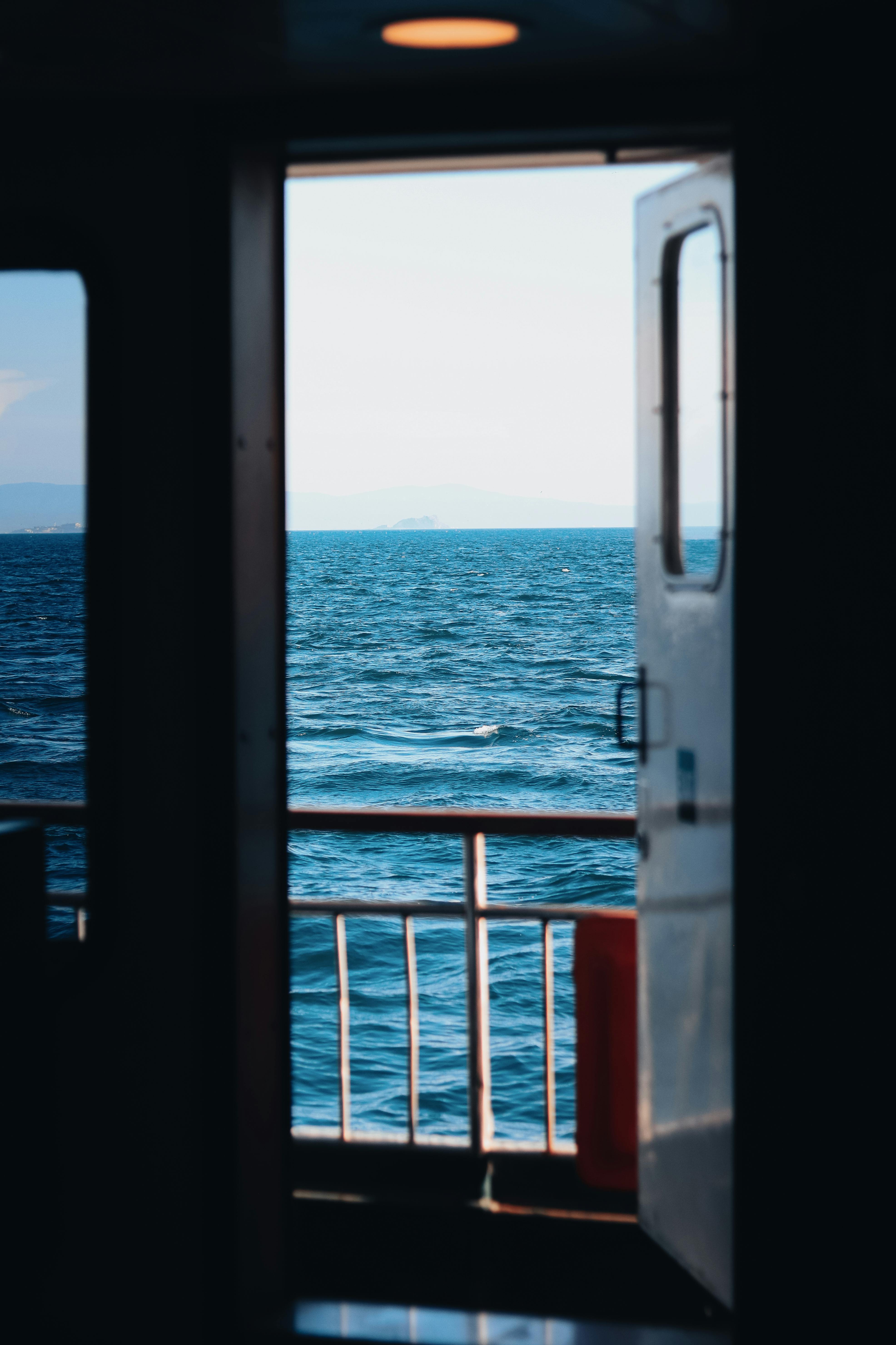A peaceful ocean view framed by a ferry doorway, embodying travel and tranquility.