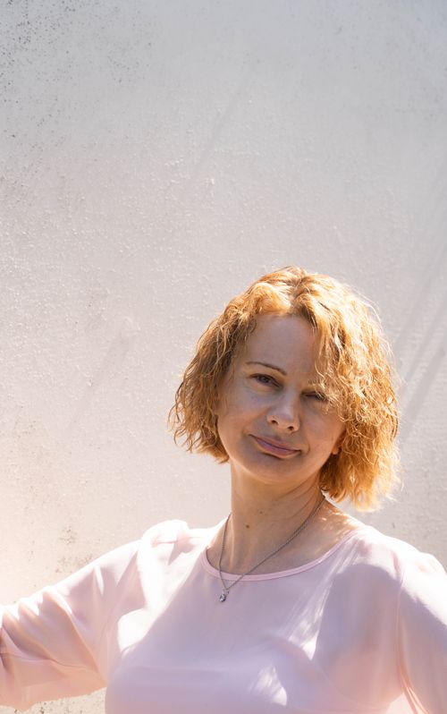Free Bright portrait of a woman with curly hair under soft sunlight against a plain background. Stock Photo