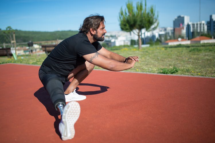 A Man Wearing Black Shirt With Amputee Leg Doing Stretching