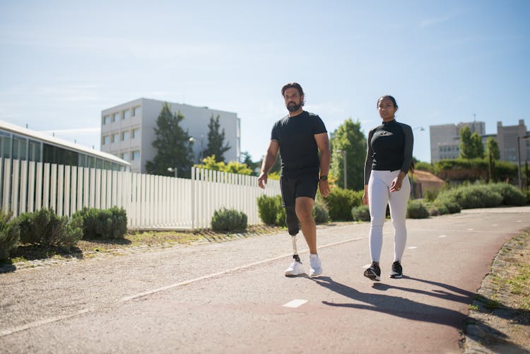 A Woman Walking With A Man With Amputee Leg