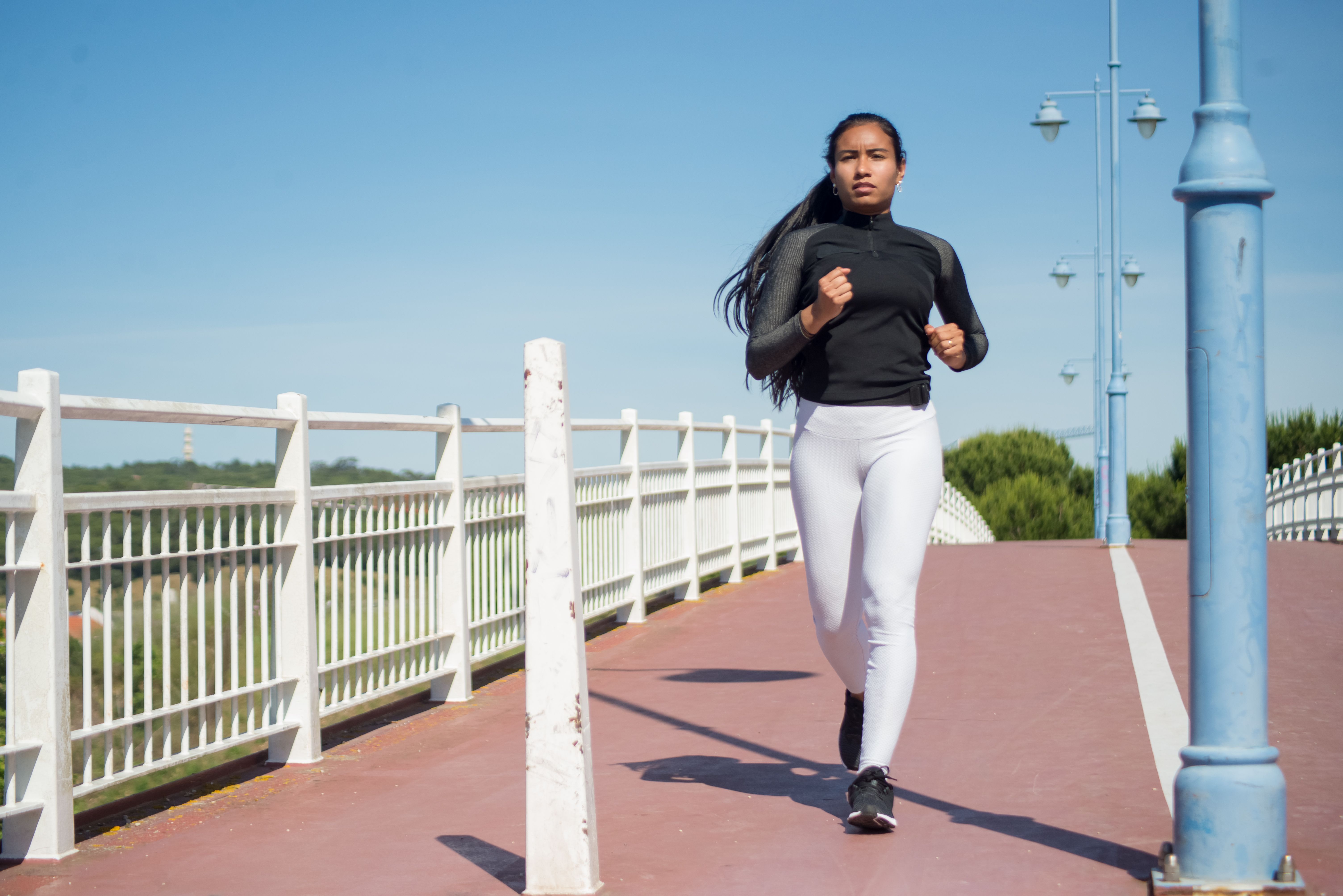 A woman jogs on a bridge in sunny Portugal, emphasizing fitness and outdoor activity.