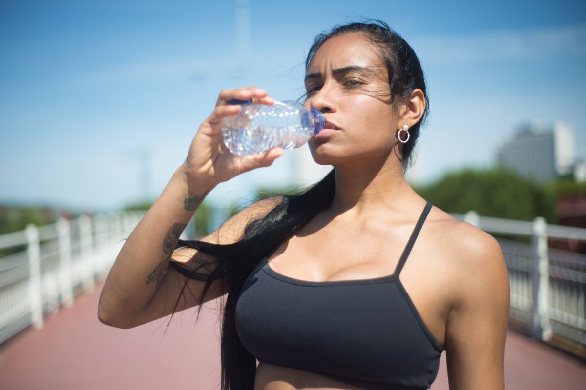 Woman drinking water outdoors on a hot sunny day