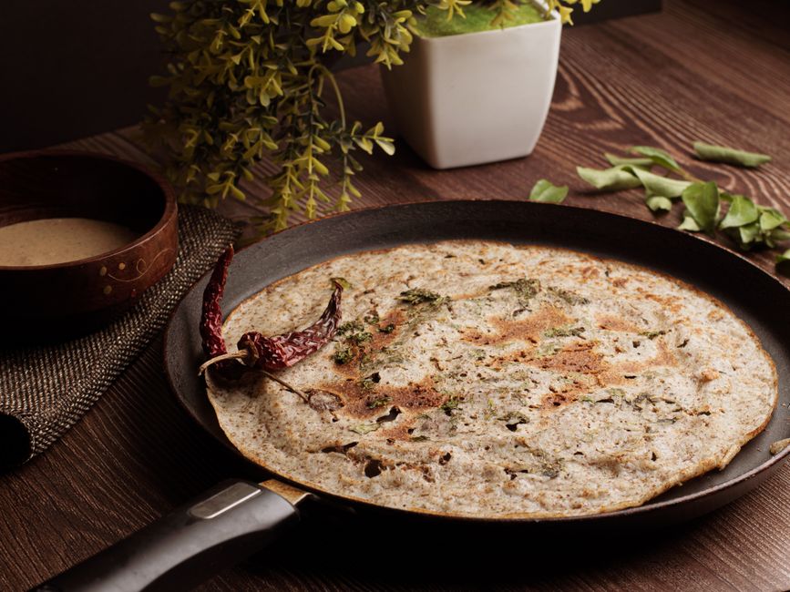 A close-up shot of a golden brown, crispy, and flaky paratha resting on a plate, with visible layers.