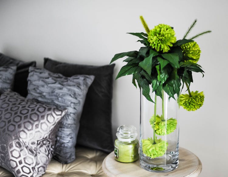 Clear Glass Vase With Green Flowers On Brown Wooden End Table