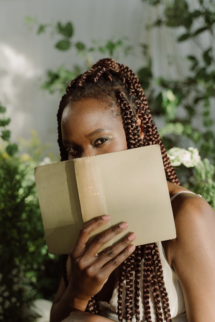 Woman With Braided Hair Covering Her Face With Book