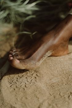 A detailed view of a barefoot resting on a sandy surface, capturing texture and natural tones.