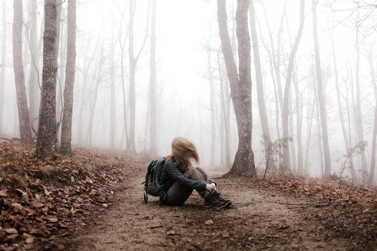 A Hiker Sitting On A Path In The Woods