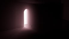 Silhouette of Person Standing Near A Doorway With Bright Light