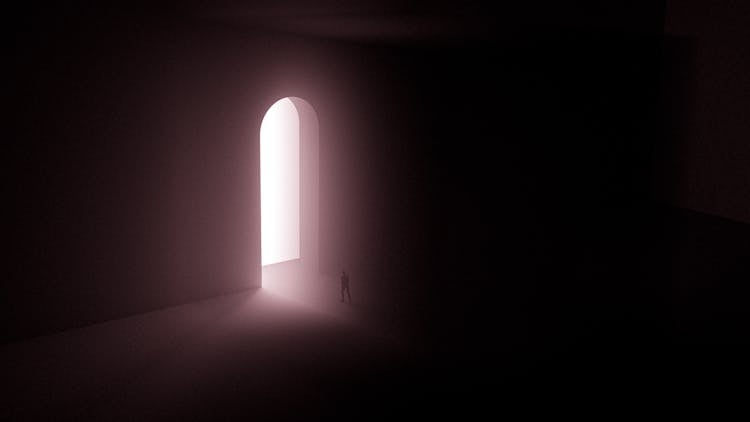 Silhouette Of Person Standing Near A Doorway With Bright Light 