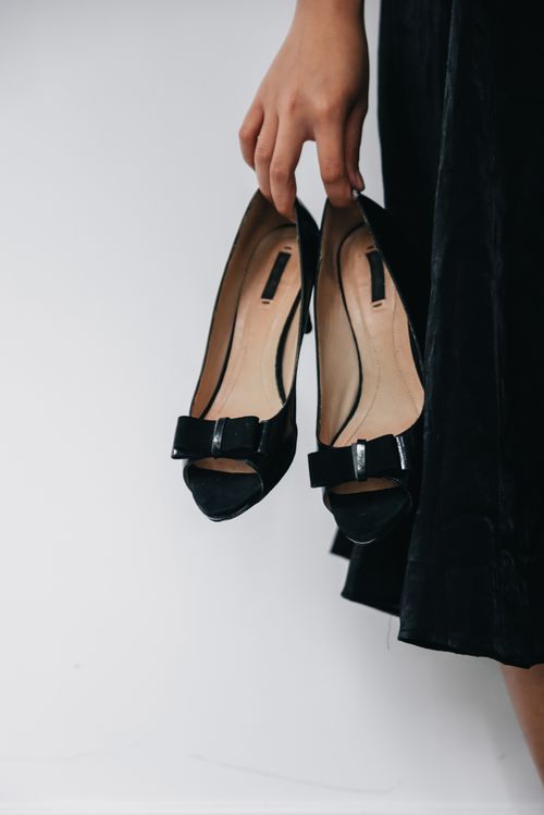 Free Stylish black high heels with a bow, gracefully held by a woman's hand. Stock Photo