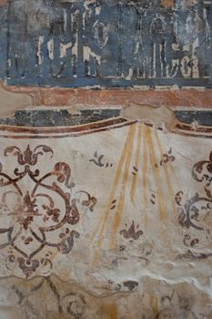 Close-up of a weathered fresco with intricate motifs on an ancient wall surface.