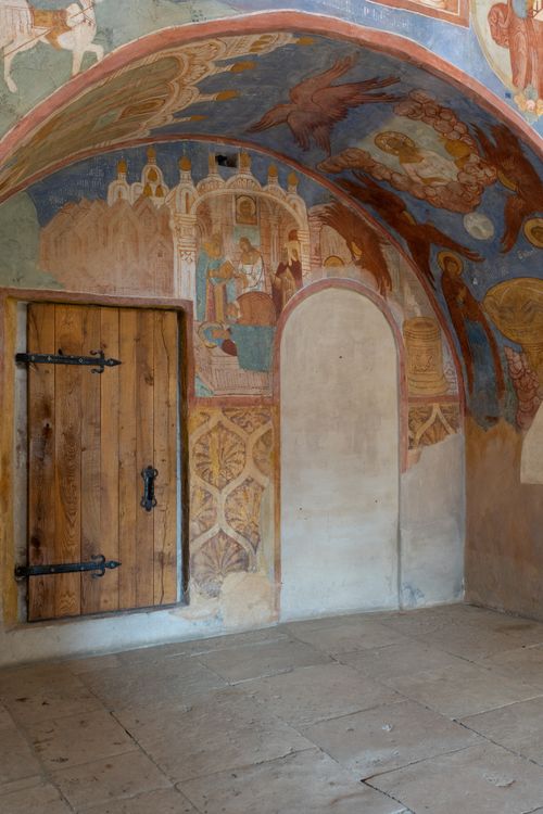 Free Detailed wooden doorway beneath colorful fresco in historic arched passageway. Stock Photo