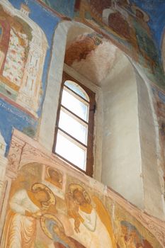 Low angle view of detailed fresco paintings and window inside a historical architecture setting.