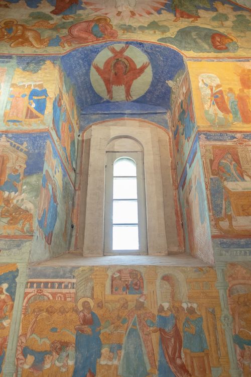 Free Beautiful interior of a church with fresco-adorned walls and a prominent arched window. Stock Photo