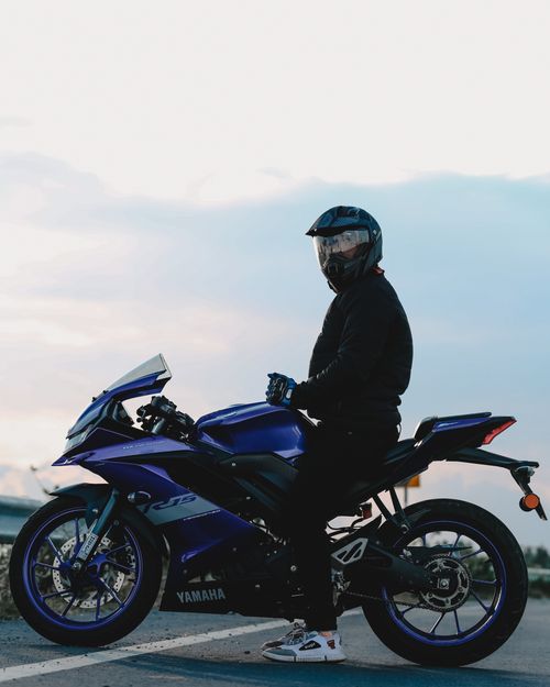 Free A motorcyclist wearing safety gear rides a Yamaha sport bike on an open road at dusk for an adrenaline adventure. Stock Photo