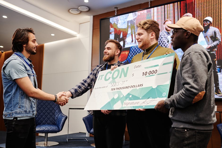 A group of men celebrating a win and receiving a large cheque at an IT conference.