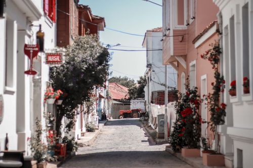 Free A picturesque cobblestone street lined with colorful facades and blooming flowers. Stock Photo