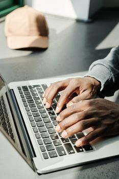 Close-up of hands typing on a laptop keyboard inside a sunlit room, emphasizing digital work.