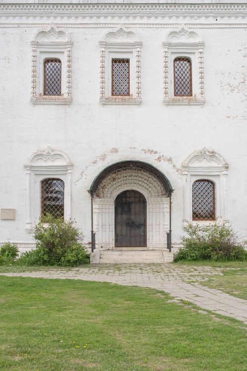 Free Old white building facade featuring an arched doorway and ornate windows. Stock Photo