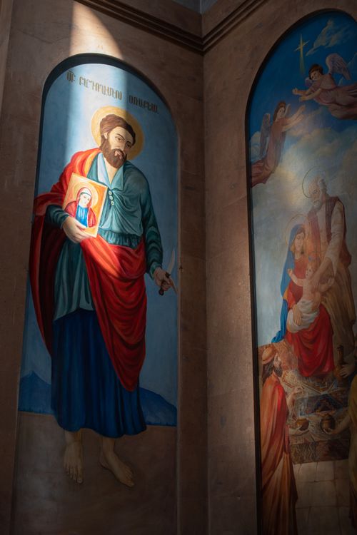 Free Stunning fresco art inside a church with a saint holding religious icons, illuminated by light. Stock Photo