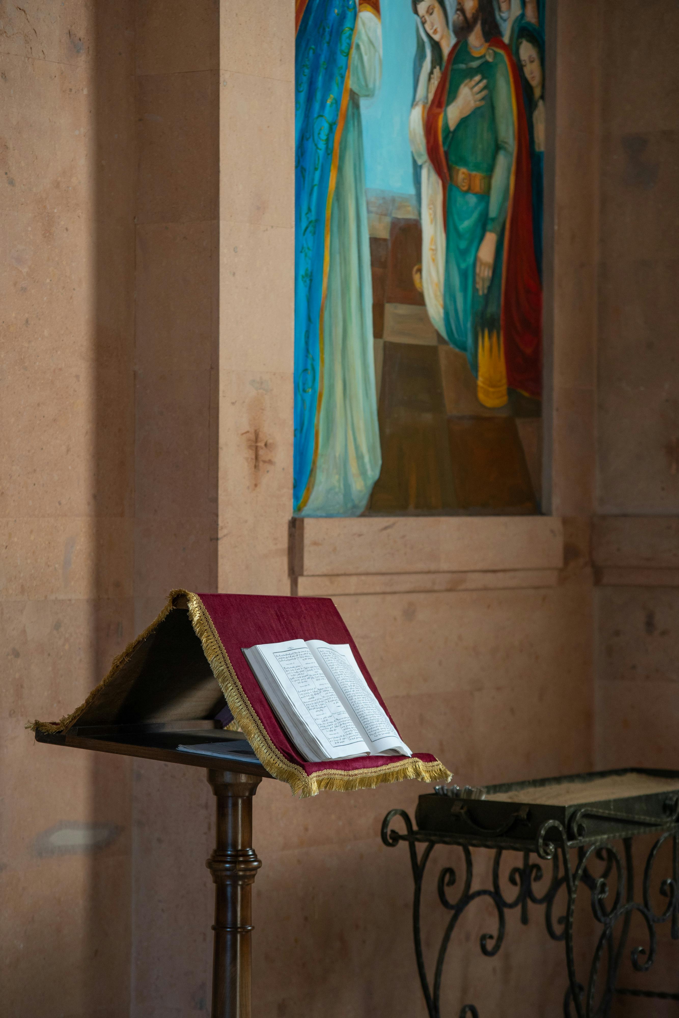 open bible lying on pulpit under fresco on wall