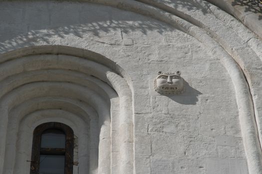 Close-up of an ornate stone carving and window on a historic building facade.