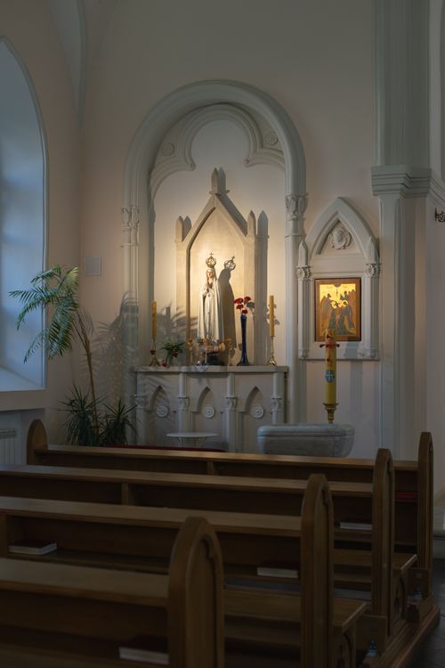 Free Peaceful church interior featuring an altar with a statue of the Virgin Mary and wooden pews. Stock Photo