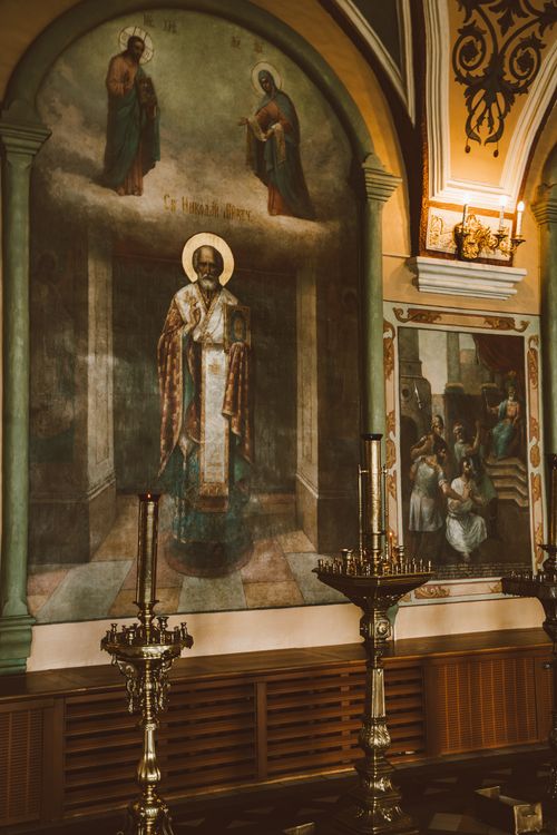 Free A beautifully ornate mural depicting religious figures inside a church, featuring candle holders. Stock Photo
