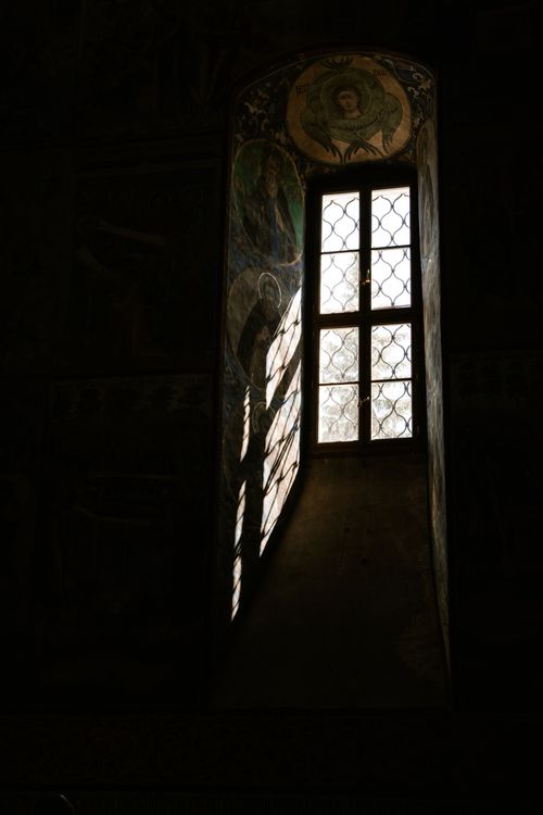 Free Atmospheric shot showcasing stained glass window and religious murals in a church. Stock Photo