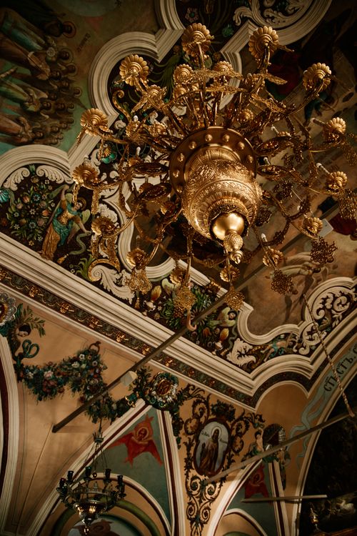 Free Elegant baroque church ceiling featuring a grand golden chandelier with intricate frescoes. Stock Photo