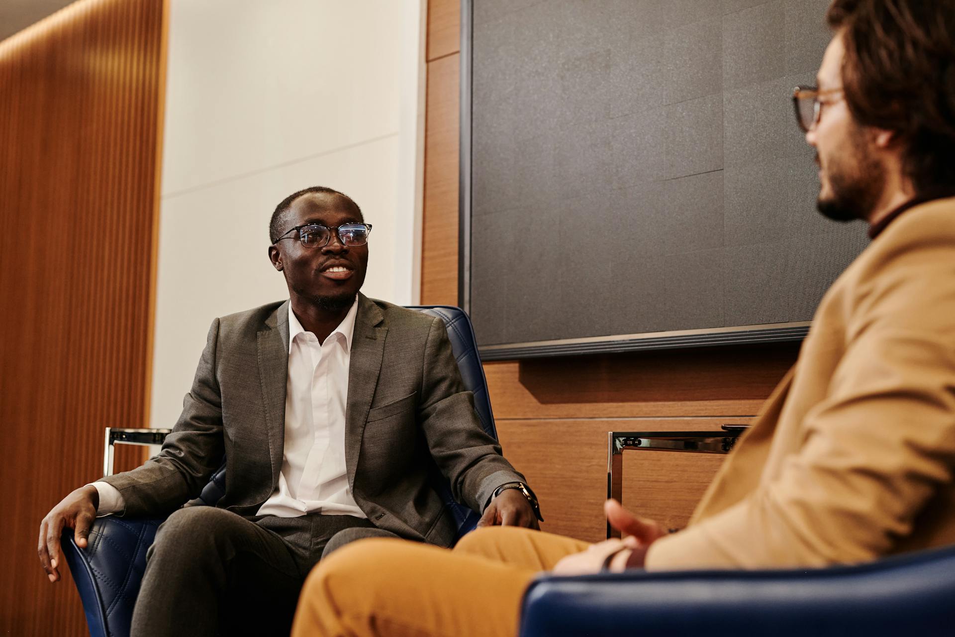 Two professionals in business attire engaged in a meeting, seated indoors.