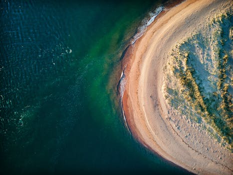 Stunning aerial view of a curved UK coastline showcasing golden sands and deep blue waters.