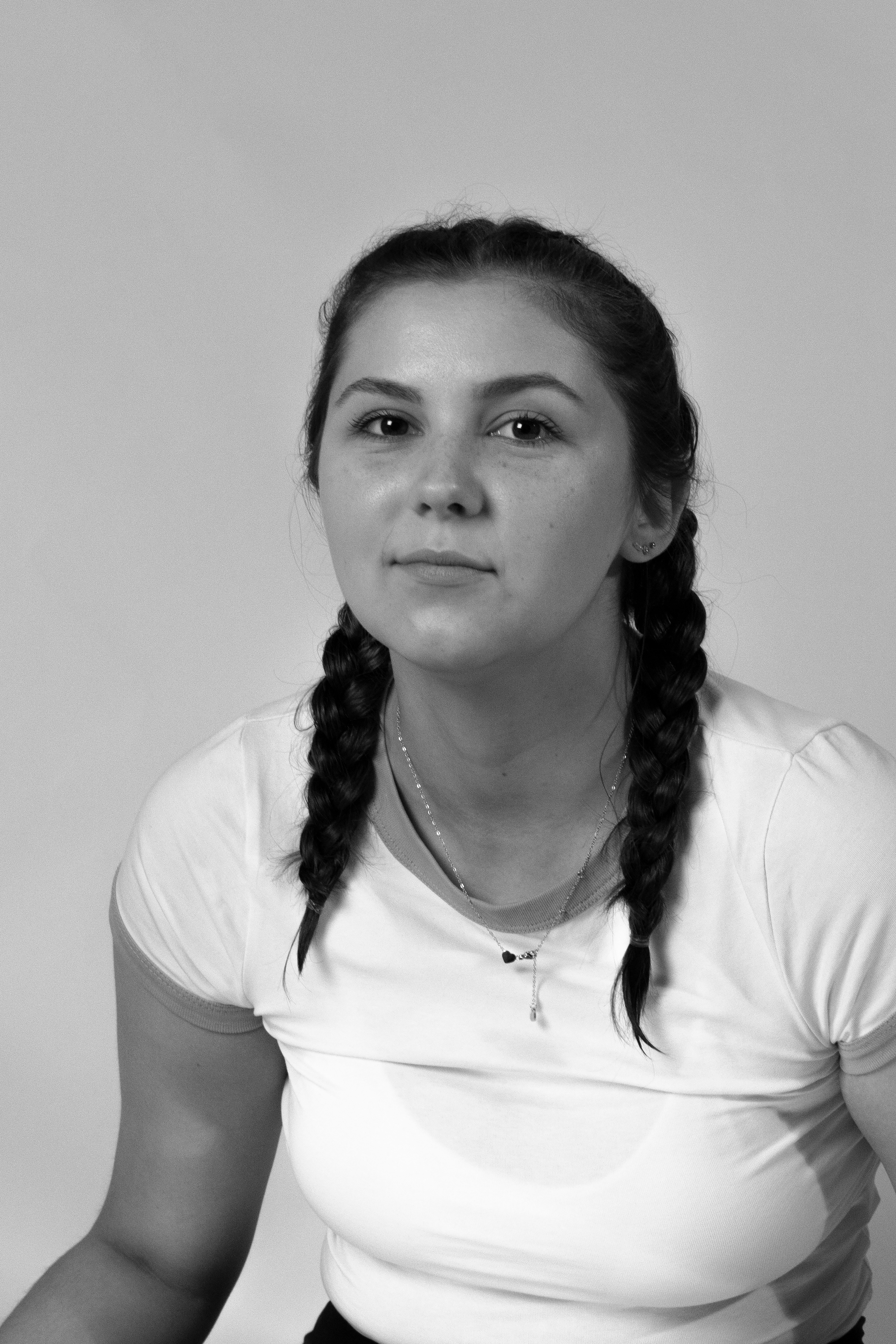 A classic black and white portrait of a woman with braided hair, wearing a white shirt.