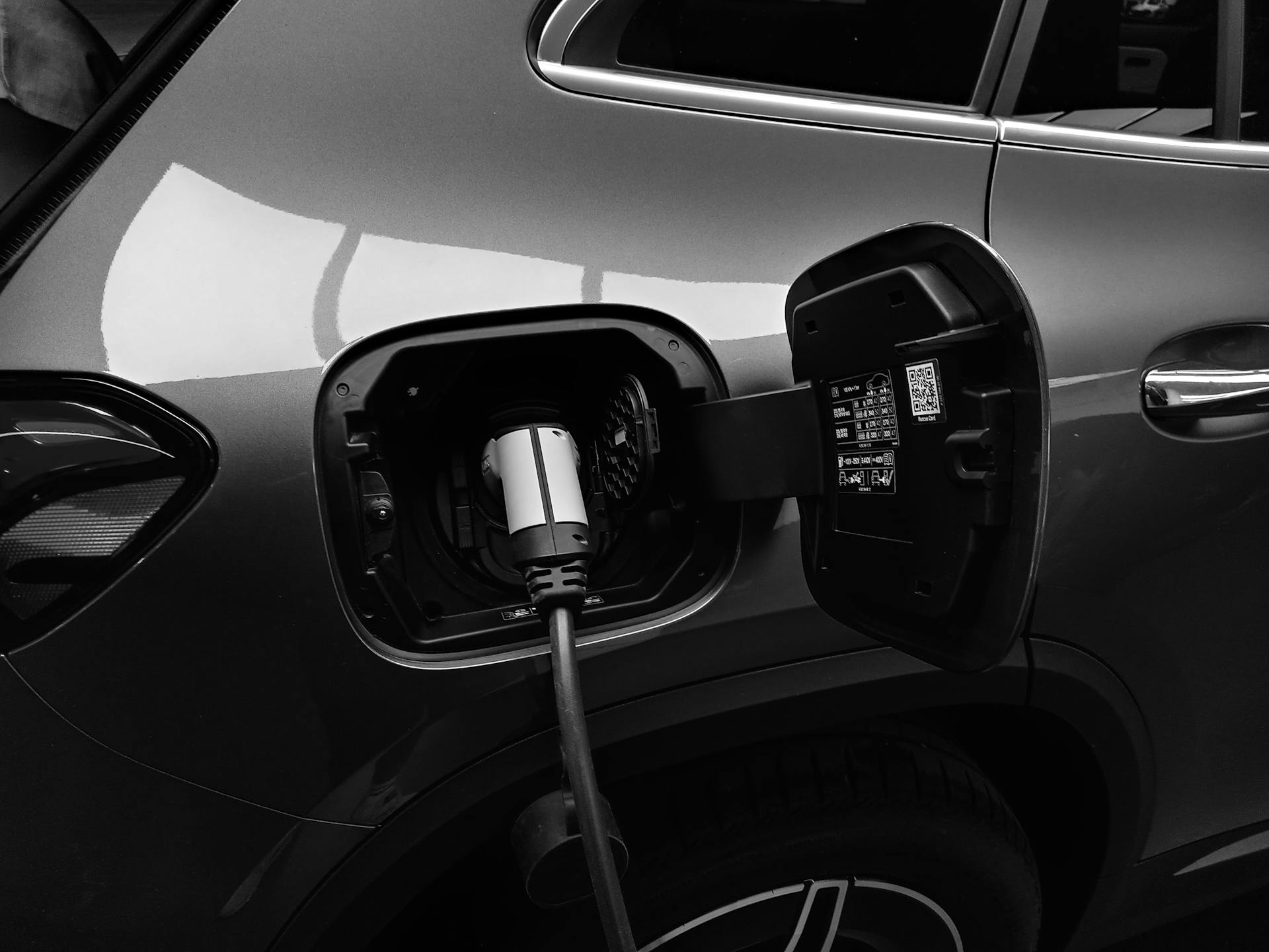 Photo monochrome de la recharge d'une voiture hybride