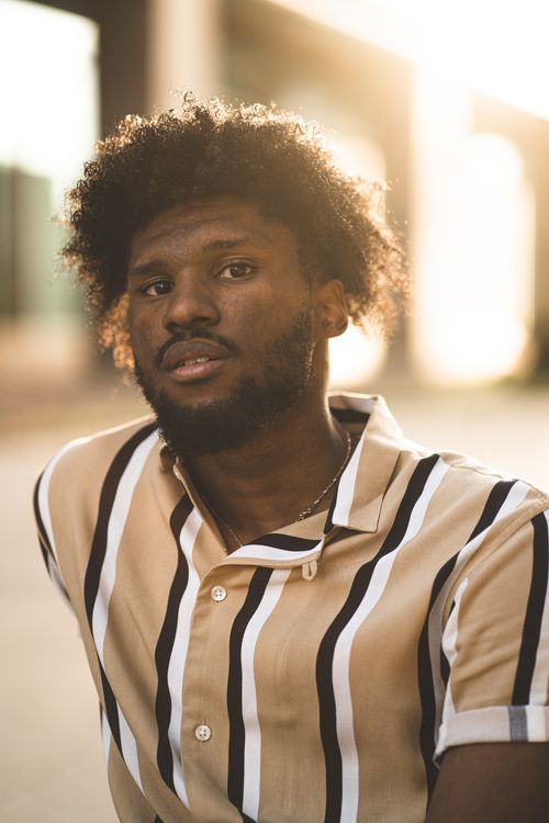 Free Captivating portrait of a man with curly hair in warm sunset lighting, exuding confidence. Stock Photo