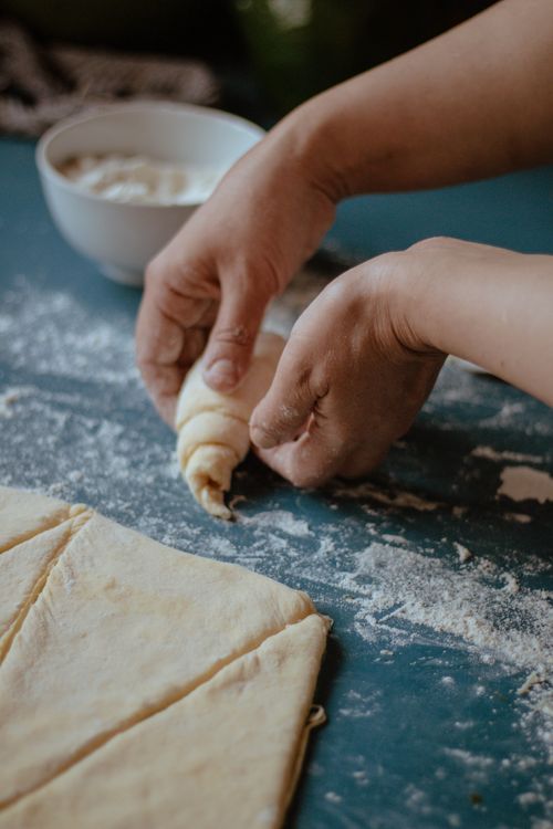 Free Close-up of hands rolling pastry dough on a floured surface in a kitchen setting. Stock Photo