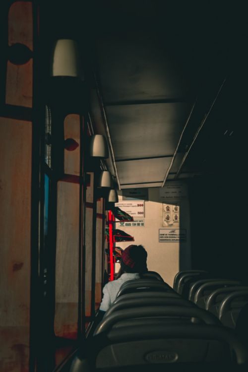 Free Silhouette of a lone commuter sitting inside a dimly lit train compartment. Stock Photo
