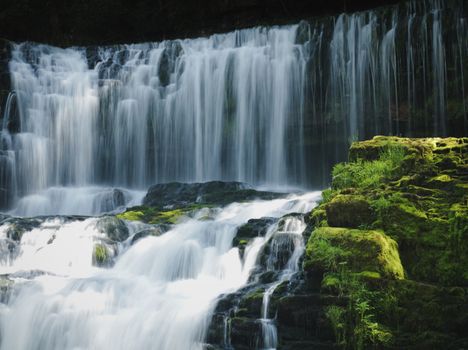 Captivating waterfall in Wales with lush moss and serene cascades.