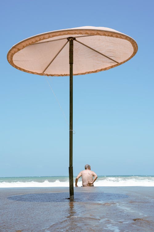 Foto profissional grátis de costa, guarda-sol, homem