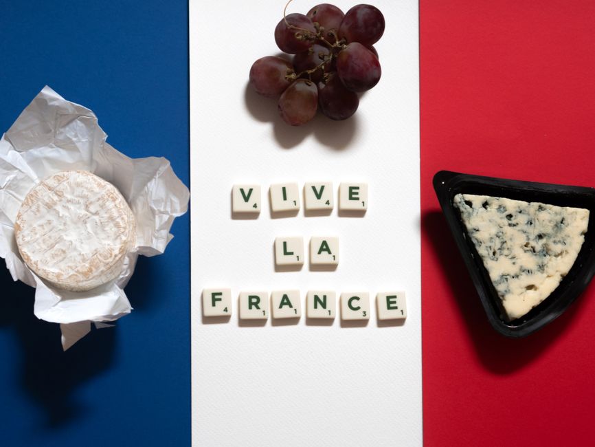 Flat lay of French cheeses, grapes, and text on French flag colors.
