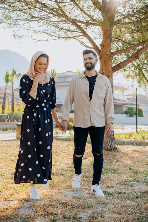 Free A happy Muslim couple walking hand in hand through a sunlit park, showcasing love and togetherness. Stock Photo