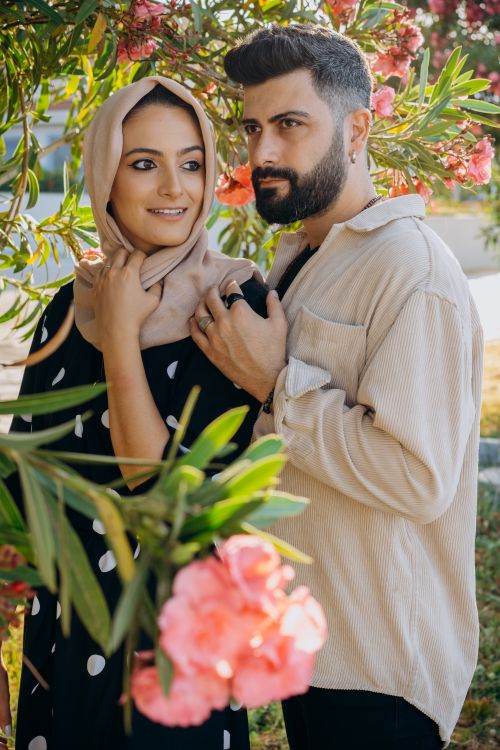 Free Couple lovingly embracing under vibrant blossoms, showcasing affection and unity. Stock Photo