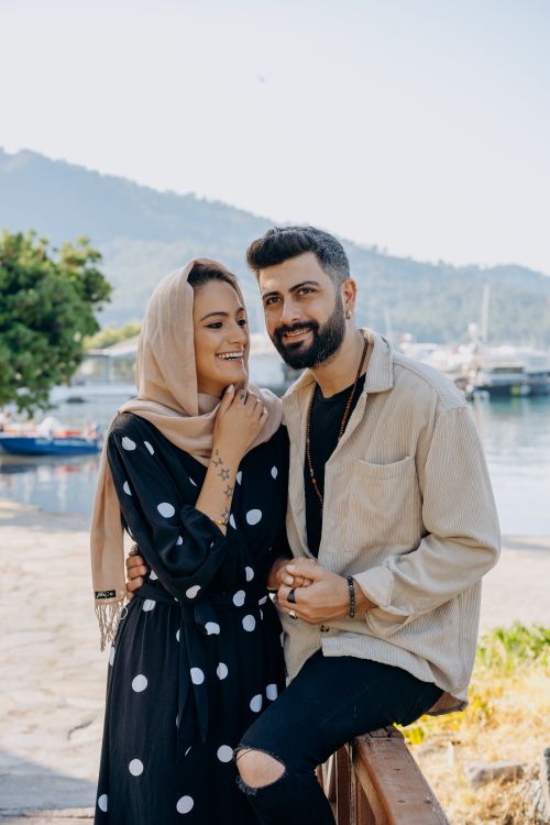 Free Smiling couple enjoying a day by the waterfront with mountain views. Stock Photo