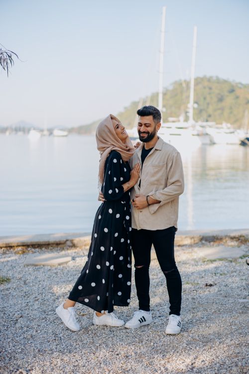 Free A joyful couple enjoys a sunny day at a marina, showcasing love and fashion by the seashore. Stock Photo