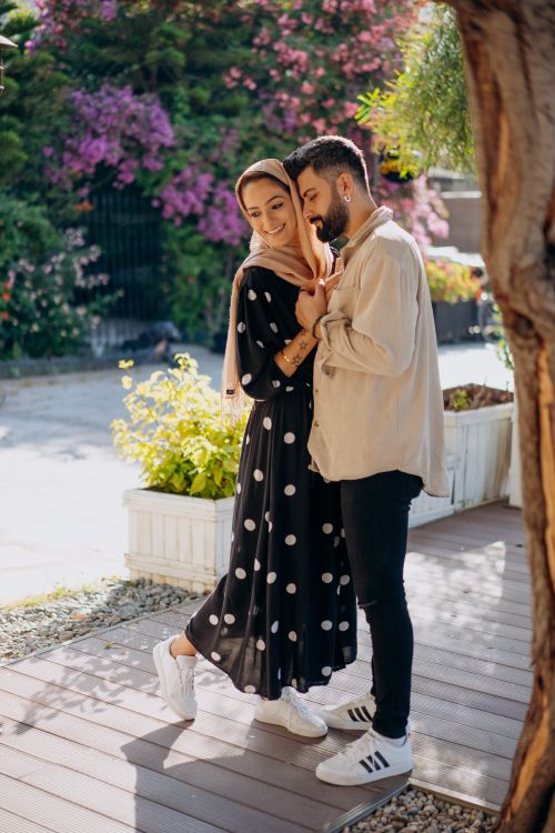 Free A romantic couple embraces outdoors in a sunlit garden, radiating love and warmth. Stock Photo