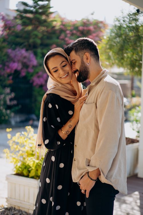 Free An affectionate couple shares a tender moment in a vibrant garden with lush greenery. Stock Photo