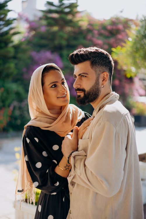 Free A loving couple sharing an intimate moment outdoors, basking in sunlight with a lush background. Stock Photo