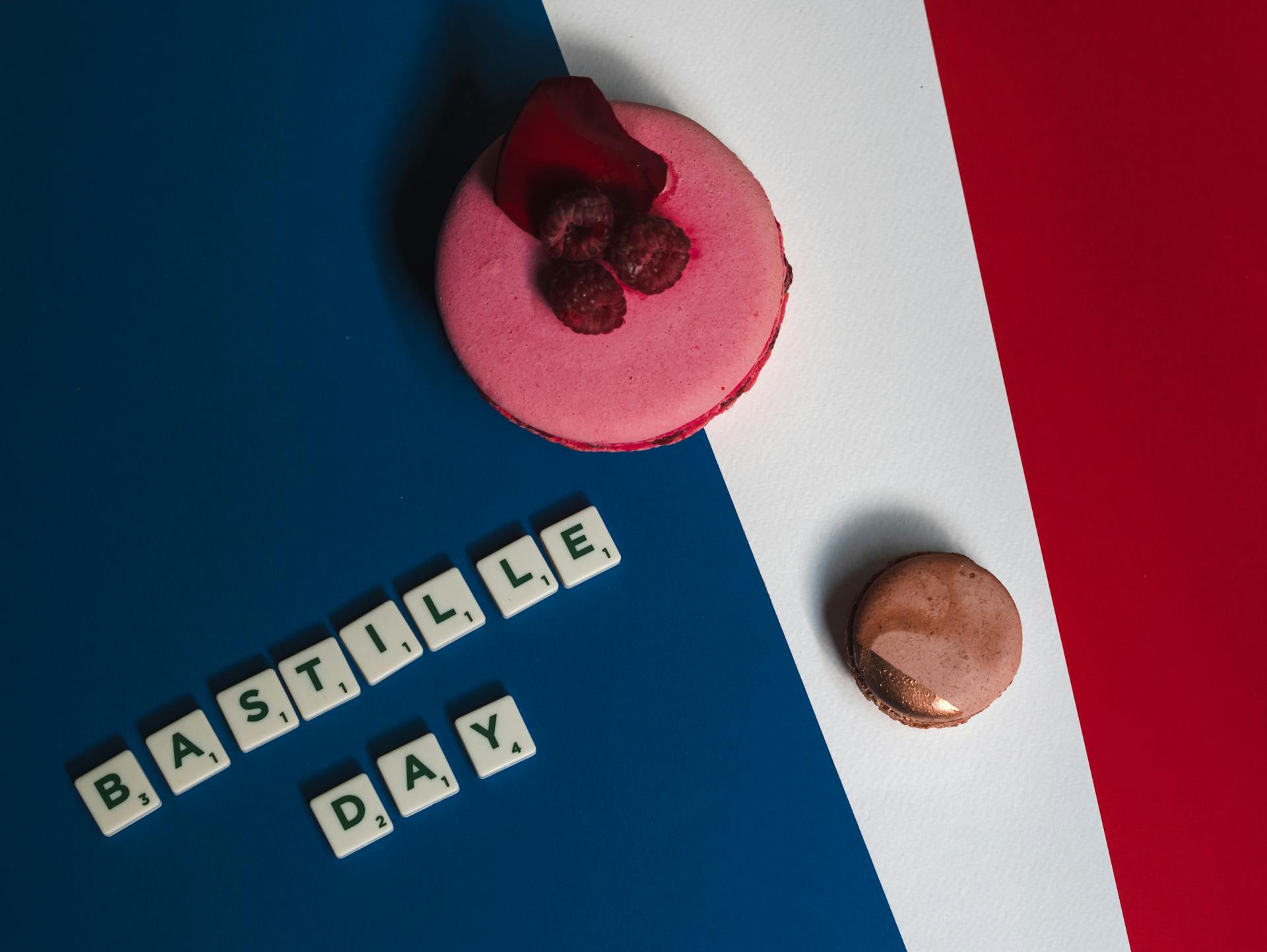 Macaroons et framboises sur une surface tricolore avec le texte du jour de la Bastille