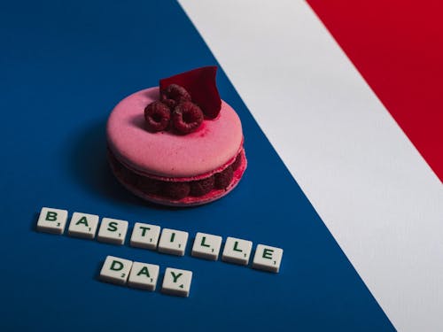 Close-Up Shot of a Pink Macaroon beside Scrabble Tiles