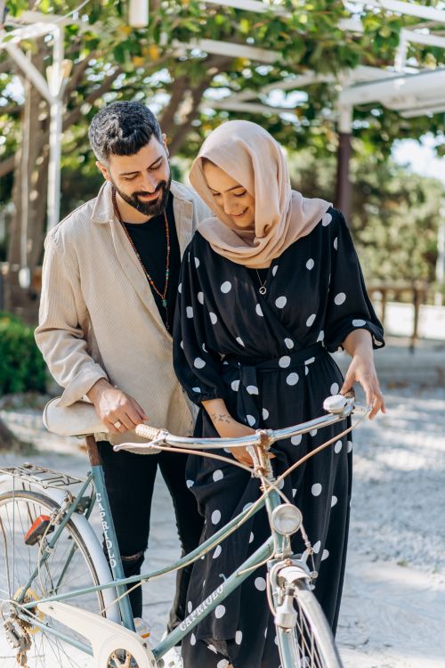 Free A smiling couple enjoying a bicycle ride in a sunny outdoor setting. Stock Photo